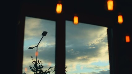 Rainy clouds seen through window. White fluffy clouds moving on sky view through window. Blurred soft warm light in cozy place