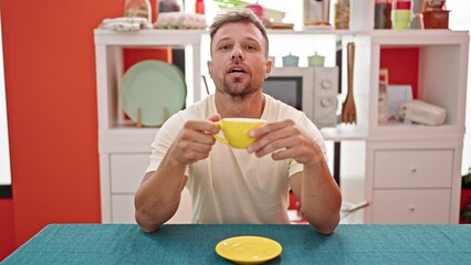 Canvas Print - Young man drinking coffee sitting on table speaking at dinning room