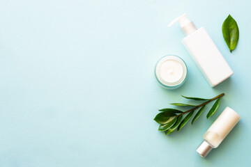 Wall Mural - natural cosmetic products. cream, serum, tonic with green leaves. top view on blue background.