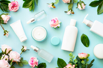 Wall Mural - natural cosmetic products on blue background. cream, serum, tonic with green leaves and flowers. ski