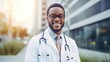 Smiling African American male doctor standing outside in a white coat