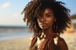 a beautiful young african dark-skinned woman posing for a photo at the beach on a vacation in summer, the sea or ocean water behind her
