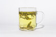 Water has just been added to a transparent cup with green tea leaves. Dragon Well green tea (Longjing tea).