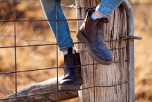 Brown Country Slip On Boots On Child Climbing Up On Gate Fence Post
