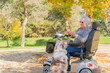 © Austockphoto - An elderly woman in a mobility scooter with her dog in an Autumn setting