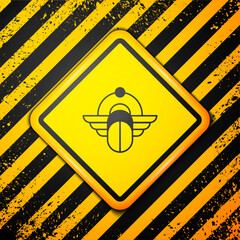 Wall Mural - Black Egyptian Scarab icon isolated on yellow background. Winged scarab Beetle and sun. Warning sign. Vector