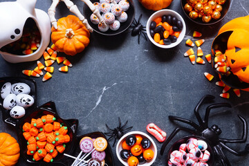 Wall Mural - Halloween trick or treat candy frame. A collection of spooky sweets. Top down view on a dark stone background with copy space.
