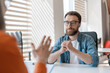 © Maria Vitkovska - Handsome serious bearded man wearing eyeglasses sitting at job interview. Group of business people talking, meeting, sharing ideas in modern office. Human resources concept