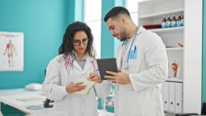 Wall Mural - Man and woman doctors standing together using touchpad taking notes at the clinic