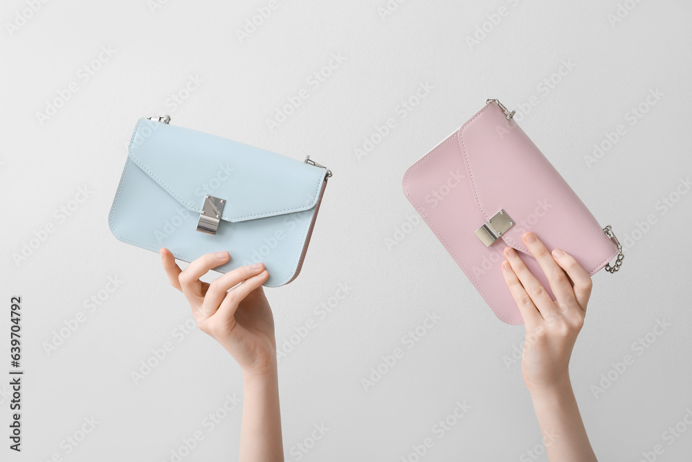 Female hands with stylish bags on white background