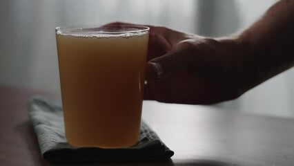 Wall Mural - Slow motion man hand take unfiltered apple cider into tumbler glass on wood table with copy space