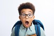 © Fred - Surprised little boy in glasses with backpack reading book on white background Back to school concept