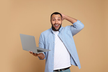 Poster - Surprised young man with laptop on beige background