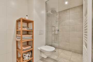 Wall Mural - a bathroom with white tile walls and flooring, there is a wooden shelving on the shelf next to the toilet