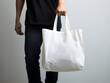 Man holding white blank tote bag for mockup template. Design tote bag mock-up, print presentation mock-up. AI generated.