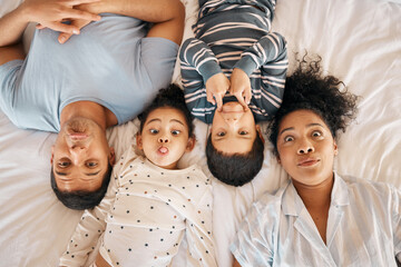 Poster - Happy, funny face and portrait with family in bedroom for playful, morning and love. Care, support and wake up with parents and children from above in bed at home for weekend, positive or relax