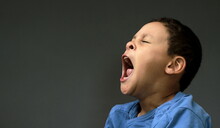 Little Child Yawning With Open Mouth On Dark Background With People Stock Image Stock Photo
