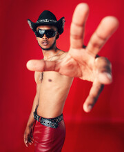 Man, Portrait And Fashion With Grunge In Studio Or Red Background With Unique Cowboy Aesthetic And Sunglasses. Gen Z, Style And Model With Pride And Hand In Photography, Retro Or Western Clothing
