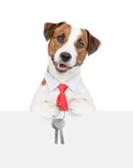 Wall Mural - Smart Jack russell terrier puppy wearing necktie holds in his paw the keys to a new apartment over a blank banner. Isolated on white background