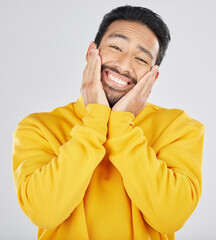 Poster - Smile, shy and hands on face of asian man in studio for in love, sweet or gesture on grey background. Happy, portrait and Japanese male model pose with emoji cheeks expression for romantic sign