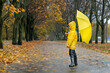 © somemeans - Child in yellow raincoat, rubber boots and an umbrella in hands is walking in the autumn park