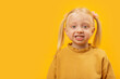 © somemeans - Little fair-haired girl with two ponytails in yellow shirt smiles and looks at the camera. Empty space for advertising mockup