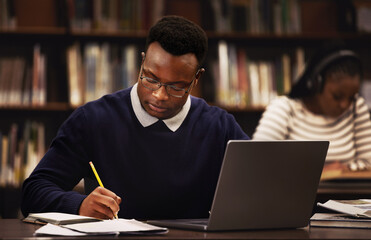 Canvas Print - Student, man and writing in library for studying, research and planning in university, scholarship and education. African person with online test and computer for language, e learning or philosophy