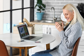 Sticker - Mature woman with cup of coffee shopping online at home