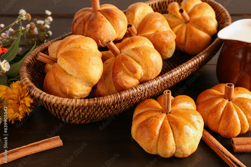 Wicker bowl with tasty pumpkin shaped buns on wooden background