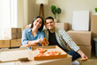 © AntonioDiaz - Couple celebrating unpacking boxes on their new house eating pizza