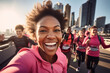 © Keitma - Black female marathon runner is taking a selfie picture while running , crowd of other runners and city view in the background