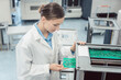 © Kzenon - woman electrical engineer wearing a white lab coat working at assembly line for electronic goods performing optical check on PCB boards