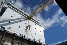 White Superstructure With Navigational Bridge On The Merchant Container Ship With Cranes And Hooks Observed From Main Deck During Sunny Day With Blue Sky With Clouds. There Are Visible Cell Guides.