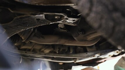 Poster - Changing engine oil in a car engine. A car service worker unscrews the engine oil drain nut on the car engine pan, the used oil is drained. Close-up.