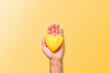 A hand holding a yellow resin heart adorned with a yellow bow, symbolizing 'Yellow September', underscoring the importance of mental health awareness and suicide prevention