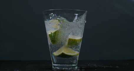 Wall Mural - Green Citrus, citrus aurantifolia, falling into a Glass of Water,