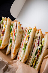 Canvas Print - Delivery food sandwiches with ham, bacon, egg, tomato, lettuce and spinach in a box.