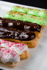 Wall Mural - French eclairs covered with vanilla, hazelnut and chocolate icing.