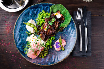 Wall Mural - Asian breakfast beef slices with cabbage, beans, egg and microgreens on wooden table.