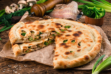 Canvas Print - Sliced closed pie with white fish, broccoli, greens and spices.