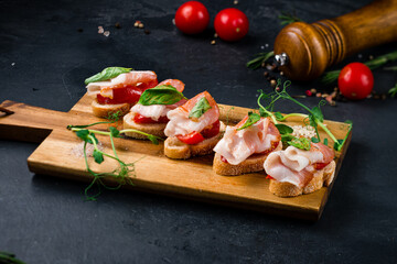 Canvas Print - Snack bruschetta with bacon slices, cherry tomatoes and spinach.