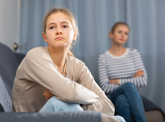 Wall Mural - Sad female and daughter sitting at sofa and having quarrel at home