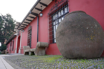 Wall Mural - Cley wine barrel and stone bench in front of Traditional adobe house in the center of a south american small town (Talca, Chile)