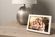 © New Africa - Frame with family photo and lamp on wooden table indoors