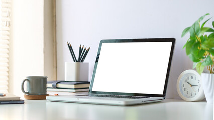 Fototapete - Mock up laptop computer, coffee cup and potted plant on white table. Empty screen for your advertise text.