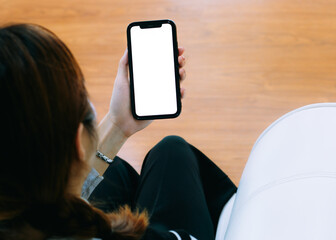 Poster - Mockup image of asian woman holding black smartphone with blank white screen at home.