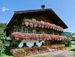 Panoramic view of traditional wooden farm with colorful flowers in Tyrol, Austria.