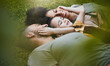 © Wesley/peopleimages.com - Care, happy and a family lying on the grass in nature for bonding, laughing and comfort. Love, smile and an interracial, father, mother and boy kid in a garden or backyard with an embrace together