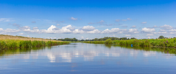 Wall Mural - Panorama of clouds reflecting in the tranquil water of the vecht river near Gramsbergen, Netherlands