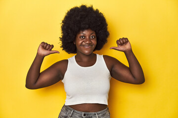 Wall Mural - African-American woman with afro, studio yellow background feels proud and self confident, example to follow.